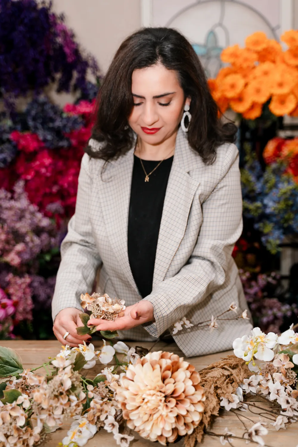 Fadila schikt zijden bloemen aan de werktafel tijdens een workshop